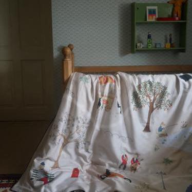 Bed with a colourful bedding featuring nature-themed designs in a room.