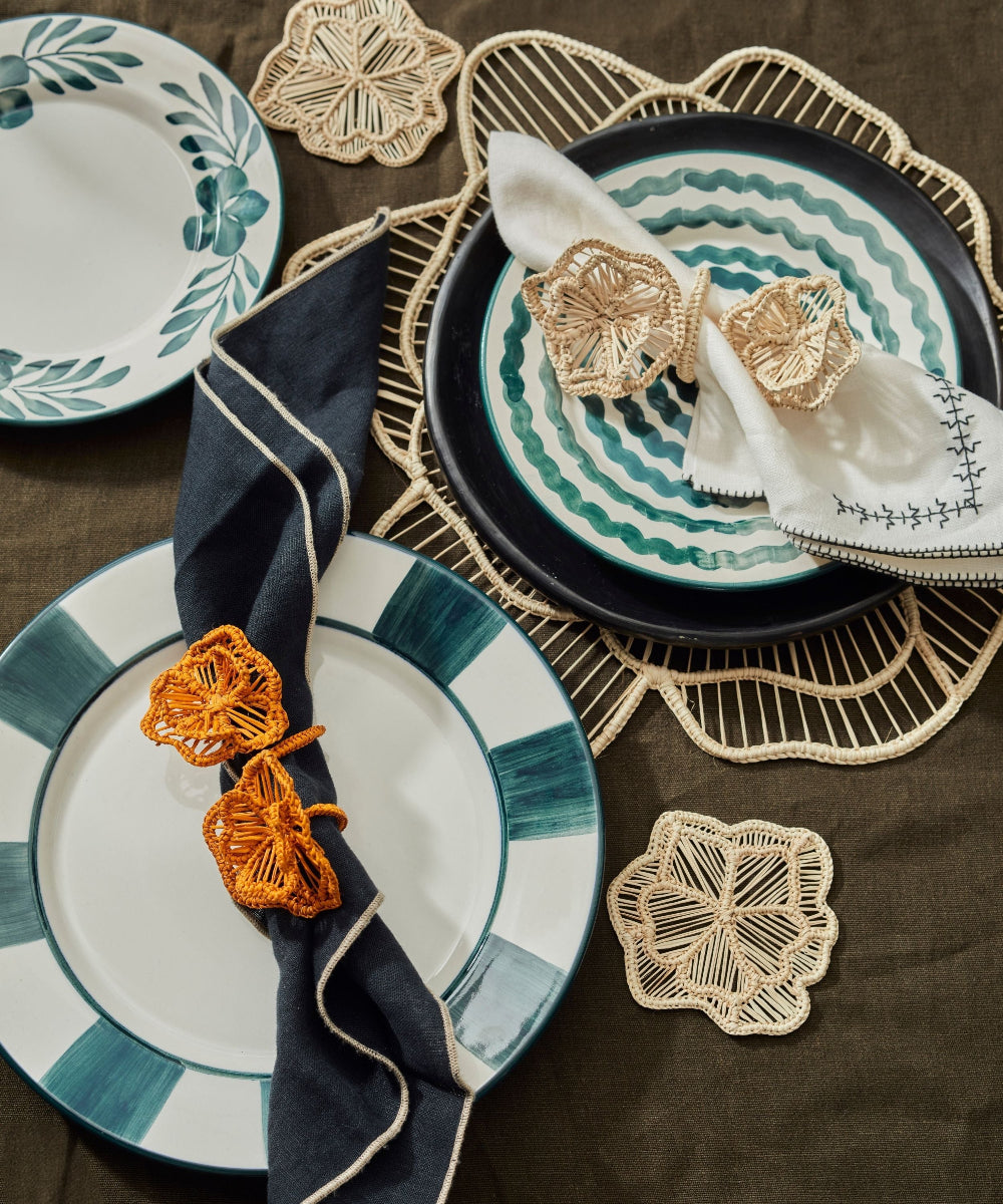 Decorative table setting with plates, napkins, and coasters on a brown surface.