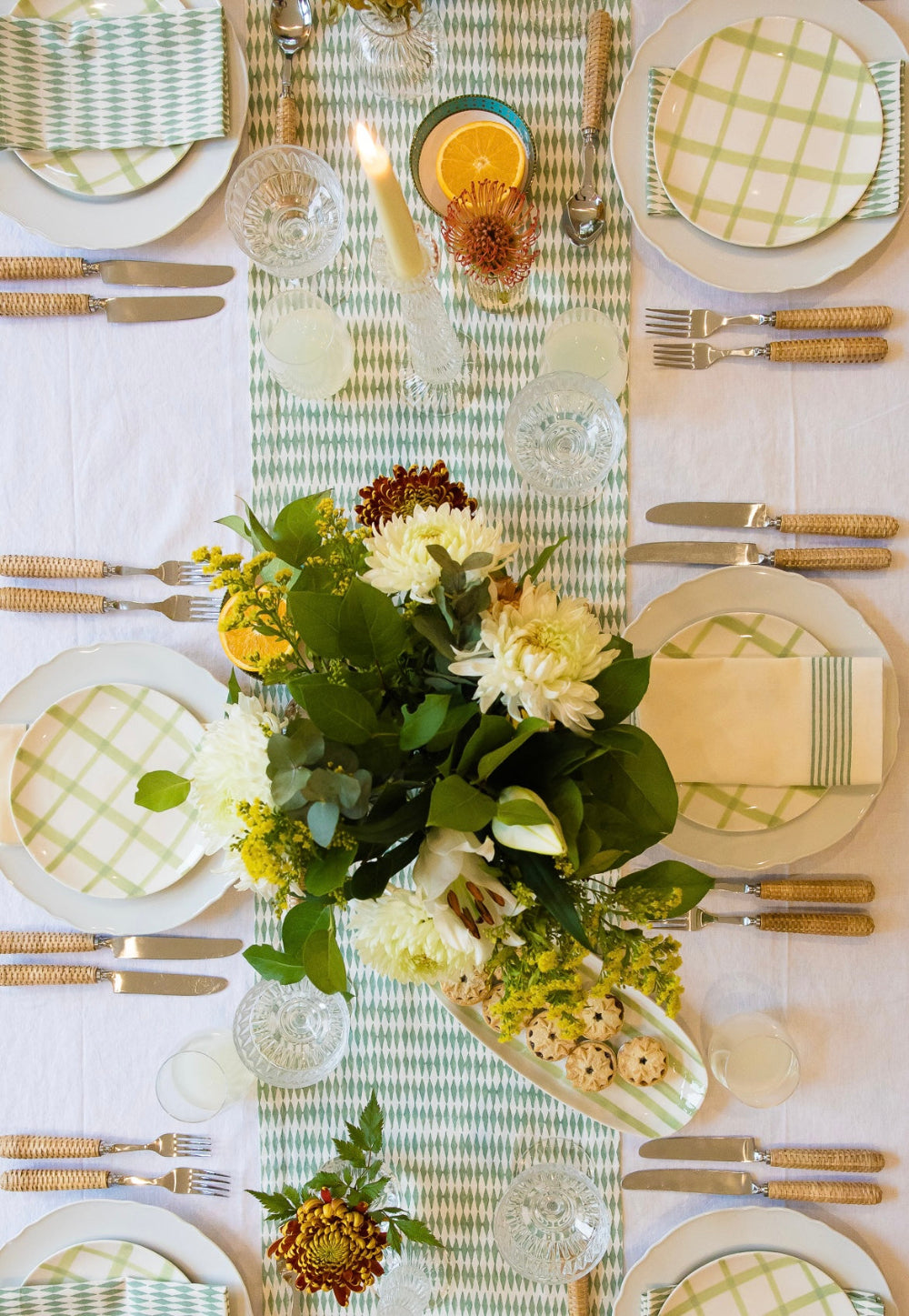 Elegant table setting with floral centerpiece, plates, and cutlery on a checkered tablecloth.