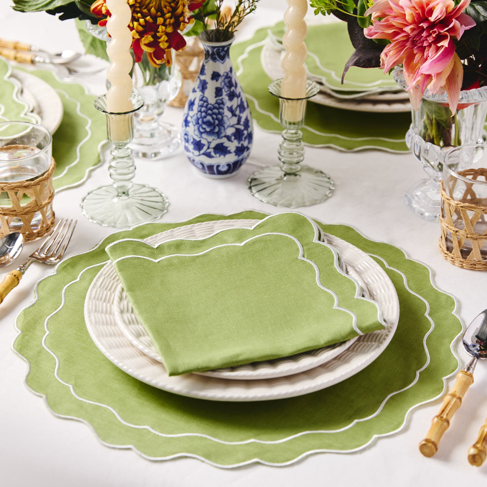 Elegant table setting with green napkin, plates, and floral decorations.