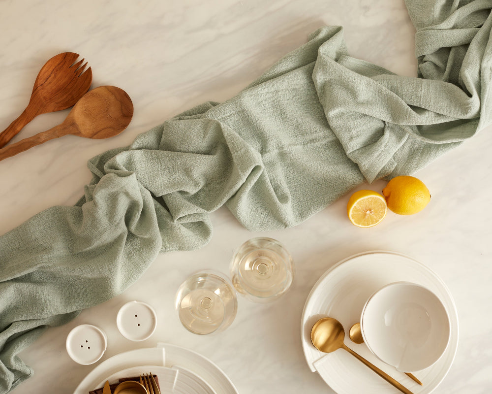 Table setting with green cloth runner, lemons, and tableware on a light surface