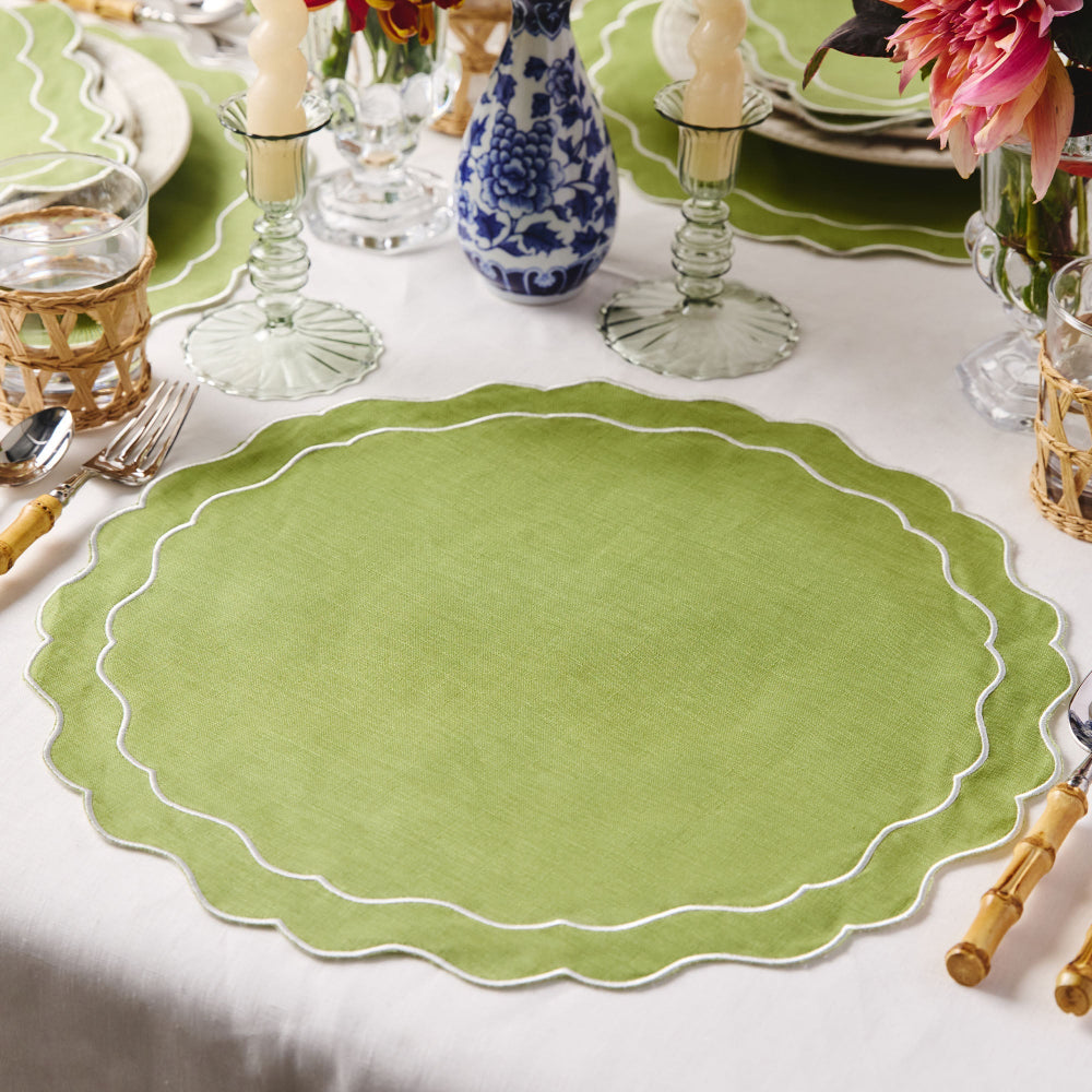 Green scalloped placemat on a table with cutlery and decorative items.
