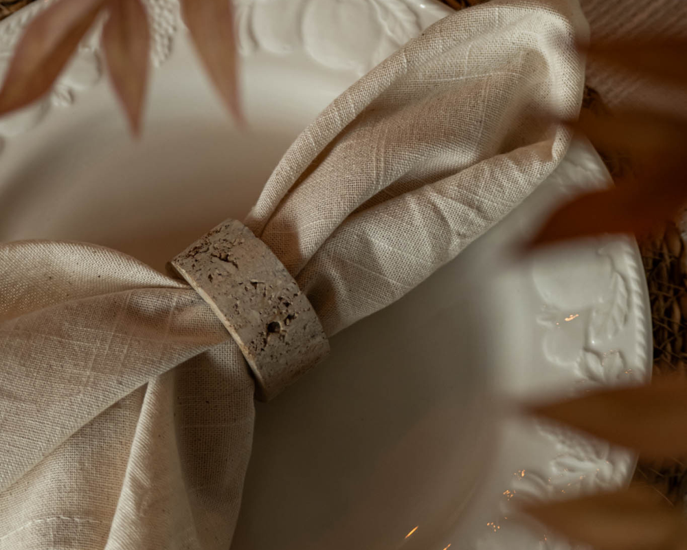 Close-up of a textured beige fabric with a travertine napkin ring