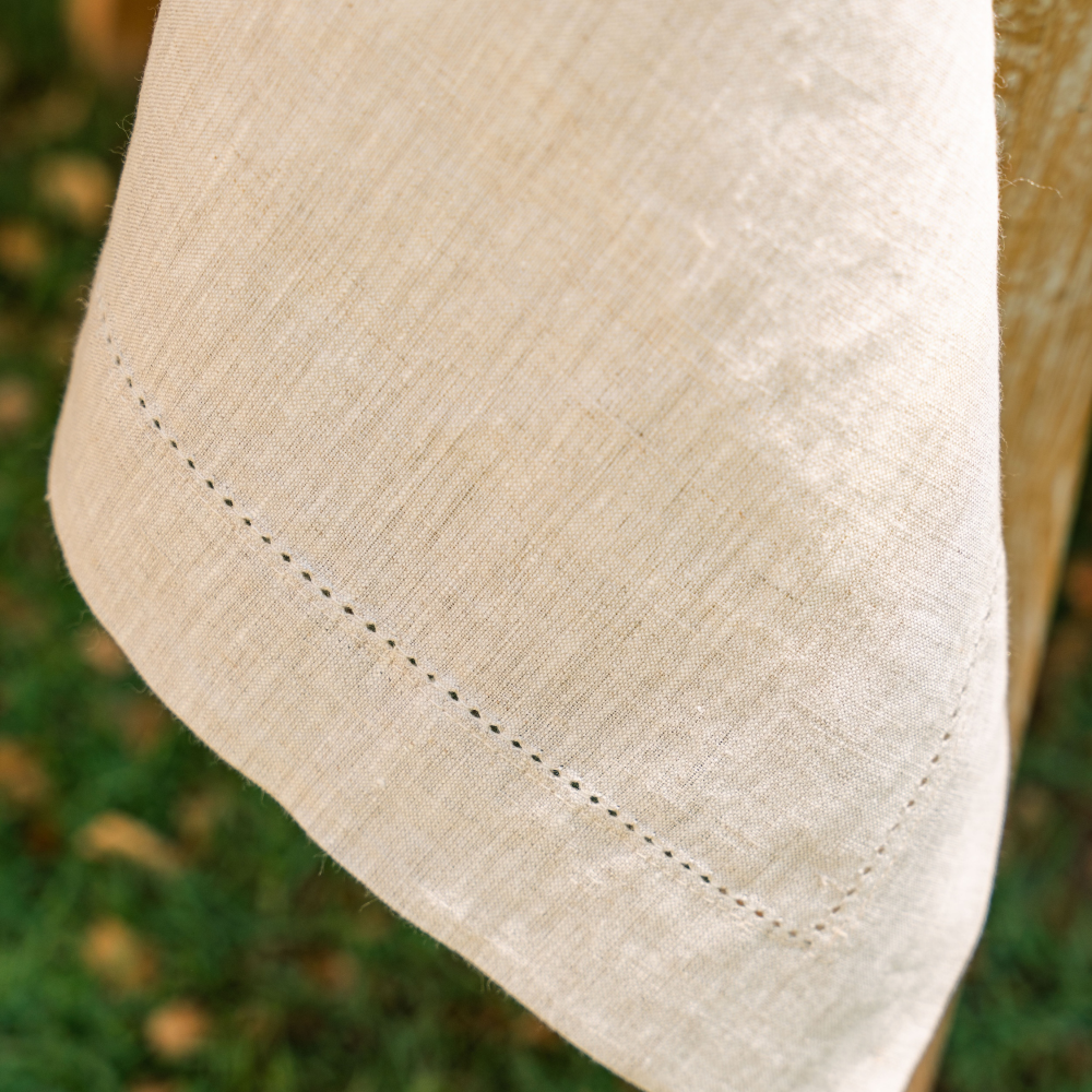 Close-up of a beige fabric with stitching detail against a blurred natural background