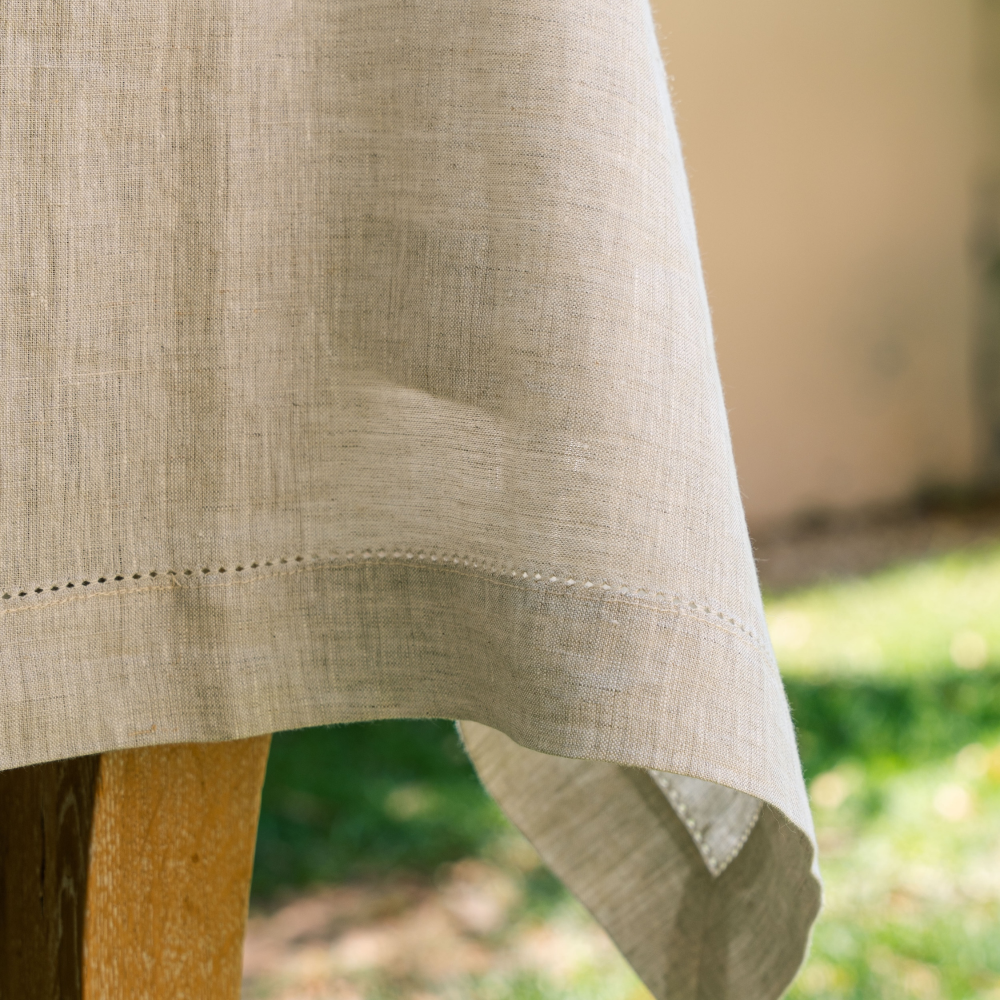 Close-up of Natural Linen hemstitched tablecloth with a blurred outdoor background
