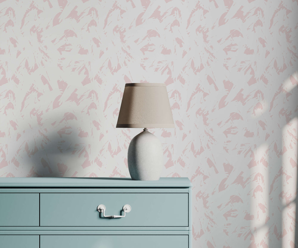 Light blue dresser with a beige lamp against a pink brush stroke design wallpapered wall