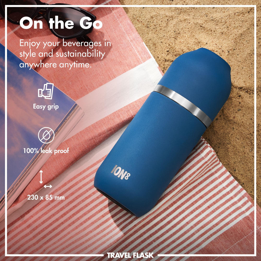 Blue travel flask with silver band on a beach towel, promotional text about its features.