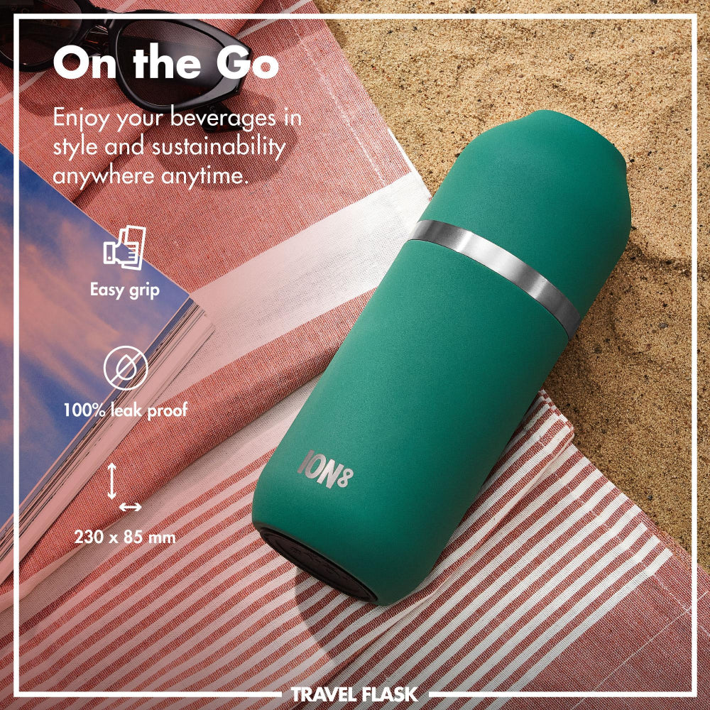 Green travel flask with text highlighting features on a beach setting