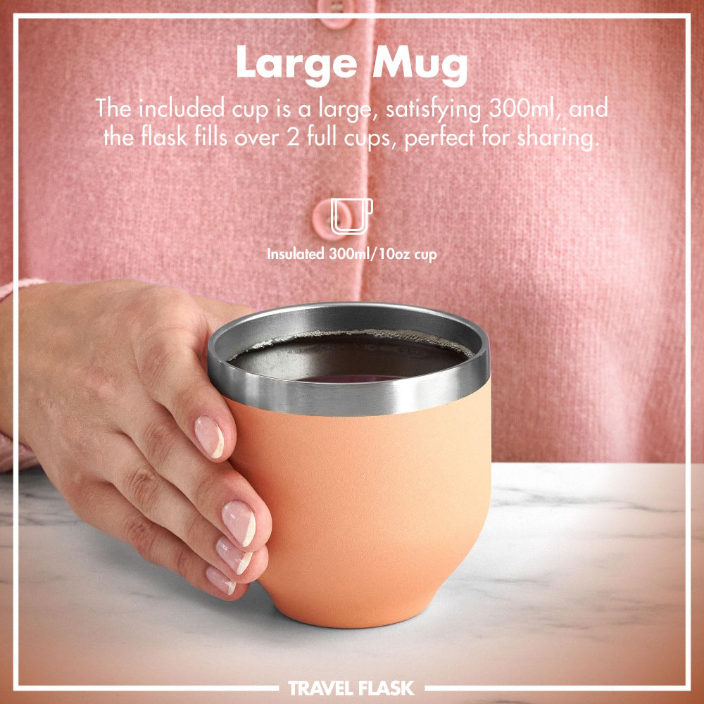 ION8 Peach travel mug with silver lid held by a hand, against a pink background.