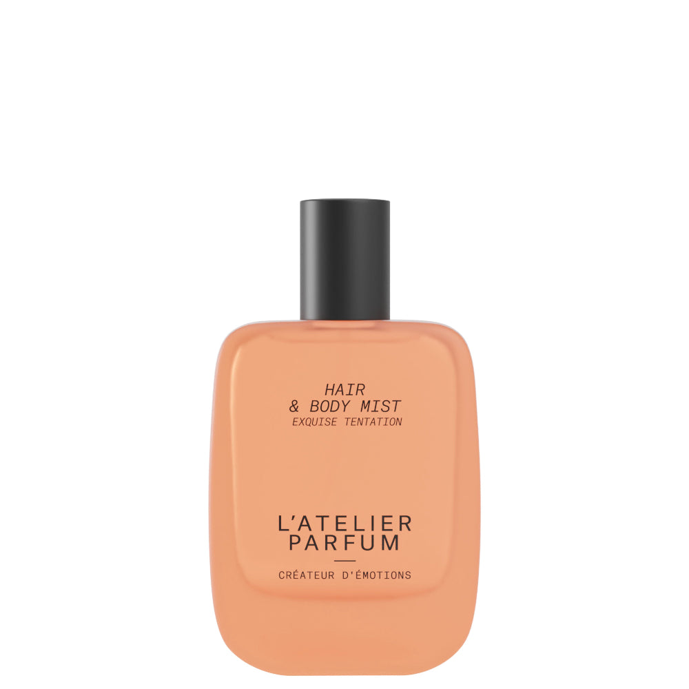 Orange bottle of hair and body mist with black cap on a white background