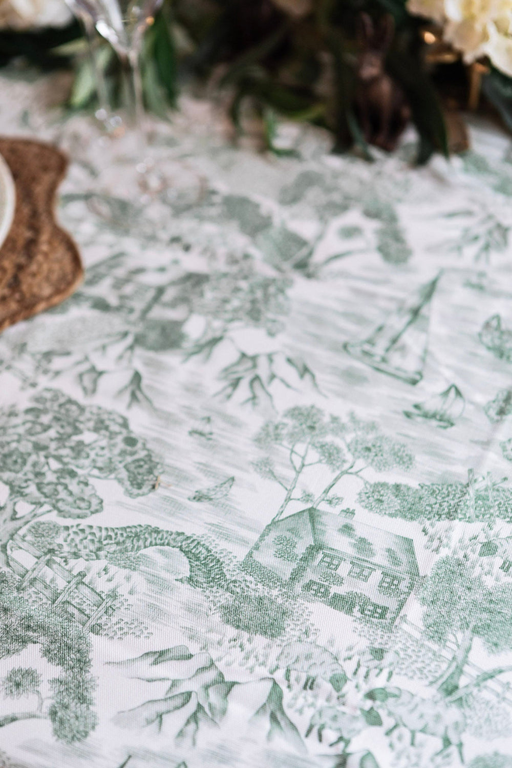 Close-up of a patterned tablecloth with green designs on a white background