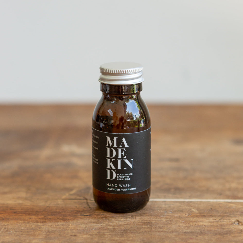 Bottle of Madekind hand wash on a wooden surface with a neutral background