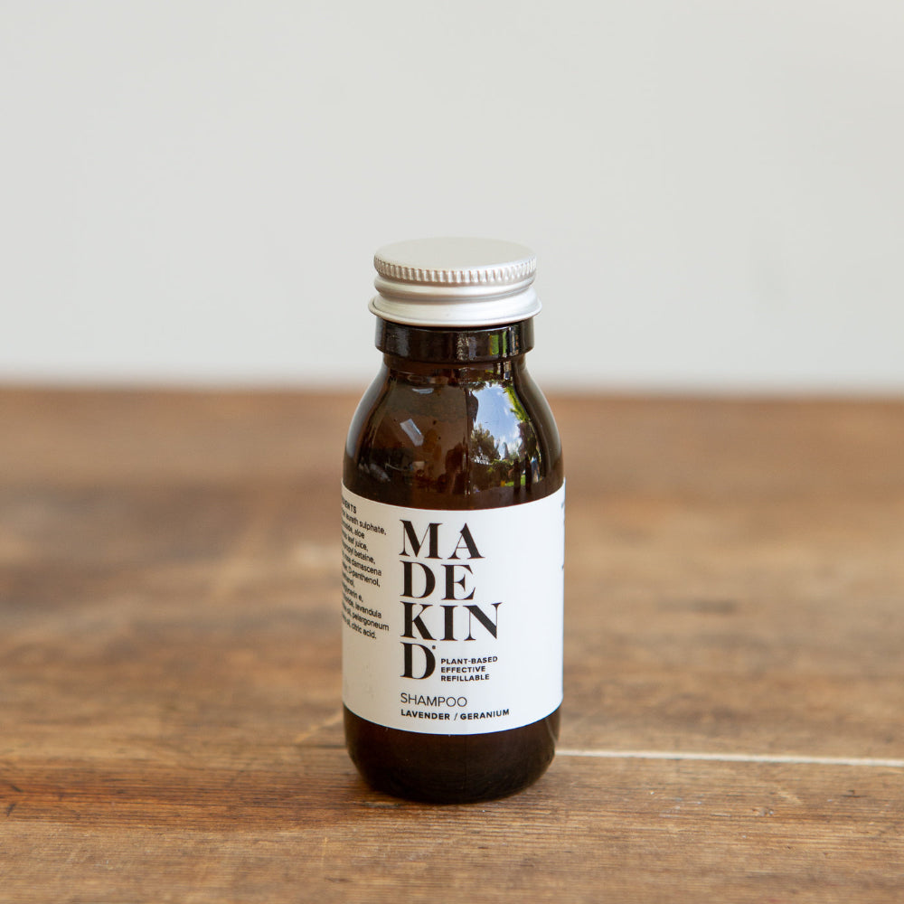 Bottle of Lavender Geranium MadeKind shampoo on a wooden surface with a white background