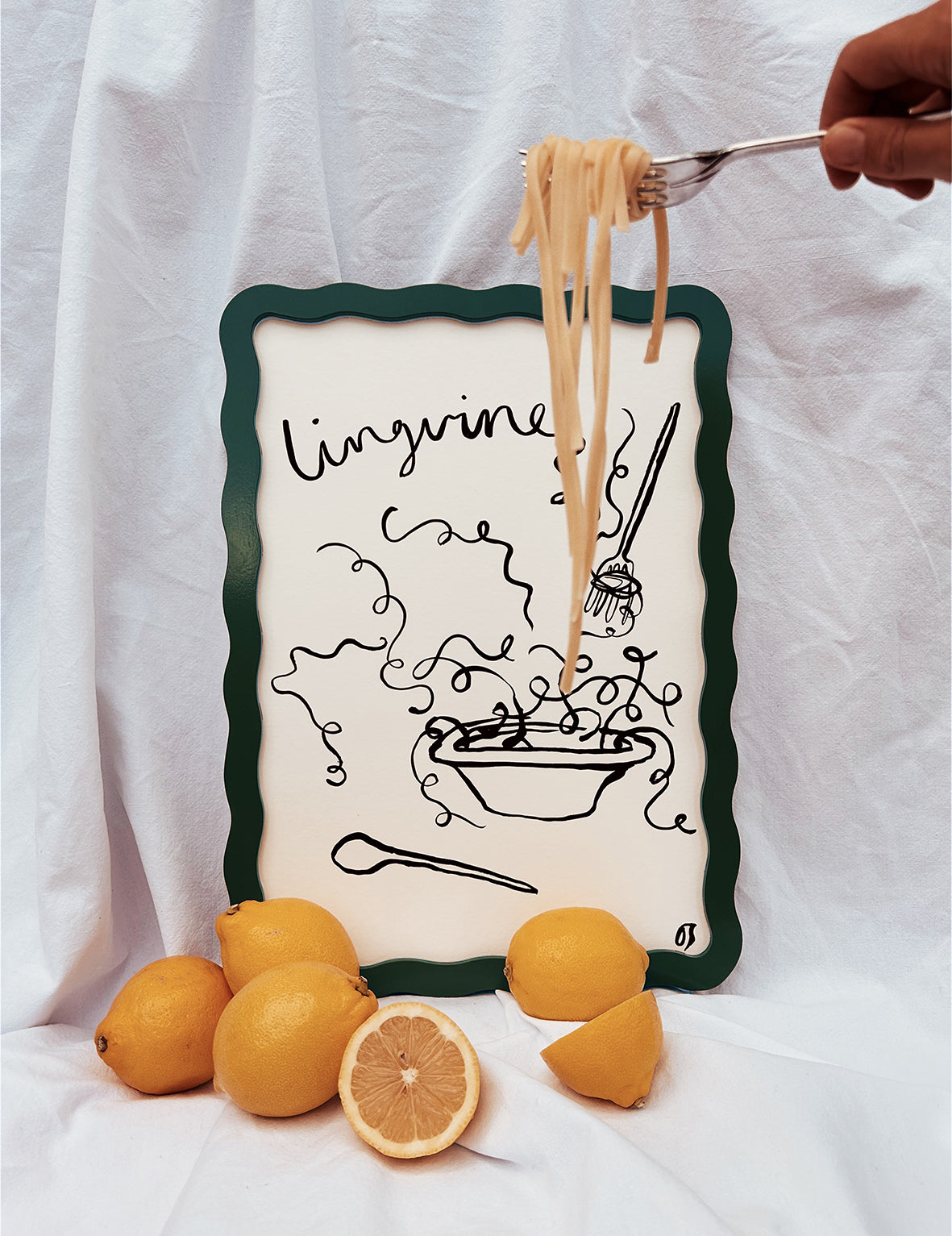 Linguine being held over a framed illustration of pasta with lemons on a white background