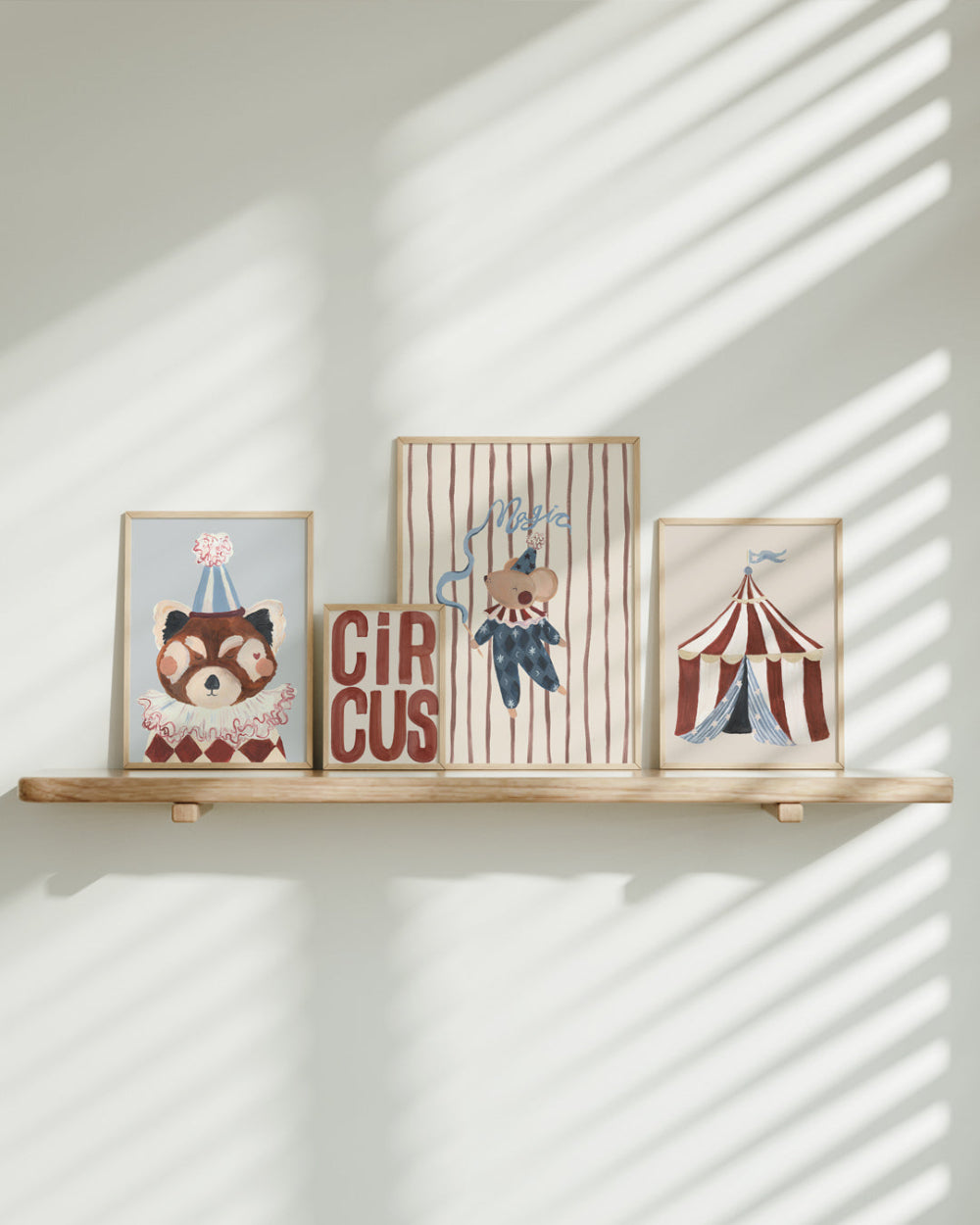 Four framed prints on a wooden shelf with sunlight casting shadows on a white wall.