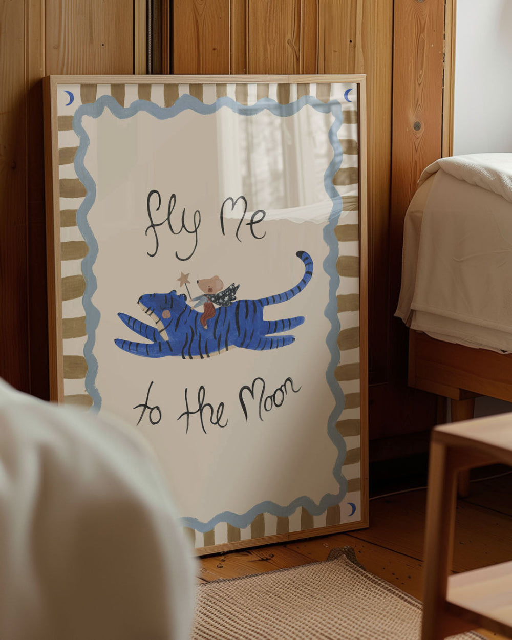 Decorative wall art with a tiger and child illustration and text 'Fly Me to the Moon' in a room setting.