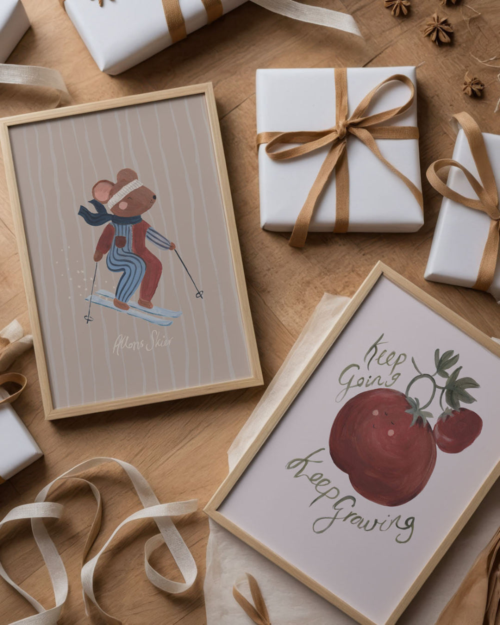 Framed artwork with a mouse skiing and an apple, surrounded by wrapped gifts and ribbons on a wooden surface.