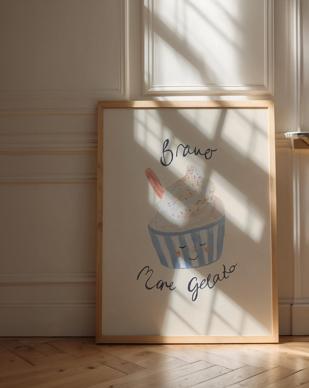 Framed artwork of a ice cream cone with text 'Bravo, More Gelato' leaning on a wall.