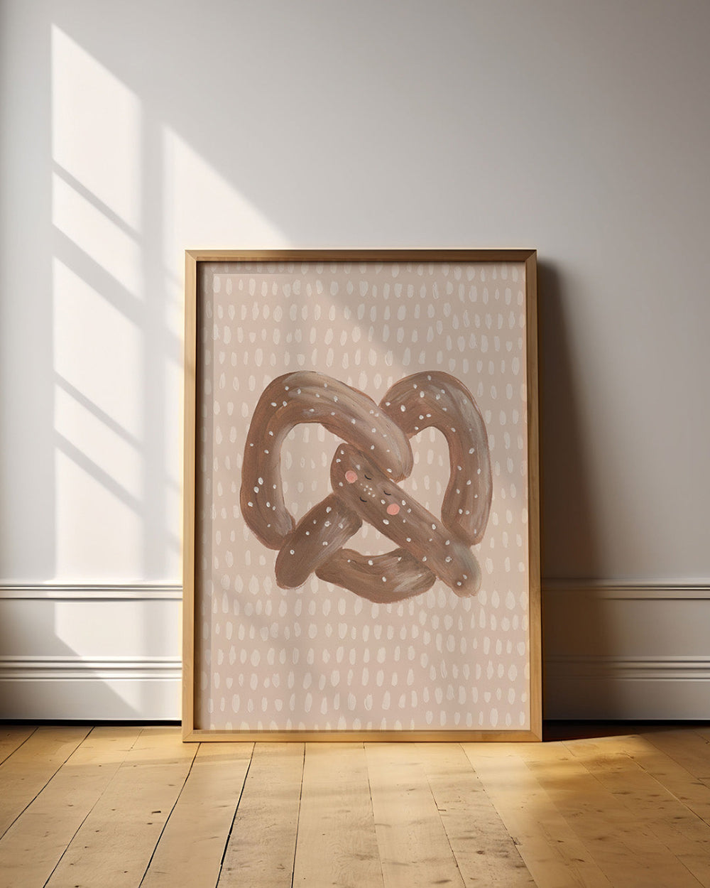 Framed artwork of a pretzel on a wall with sunlight casting shadows.