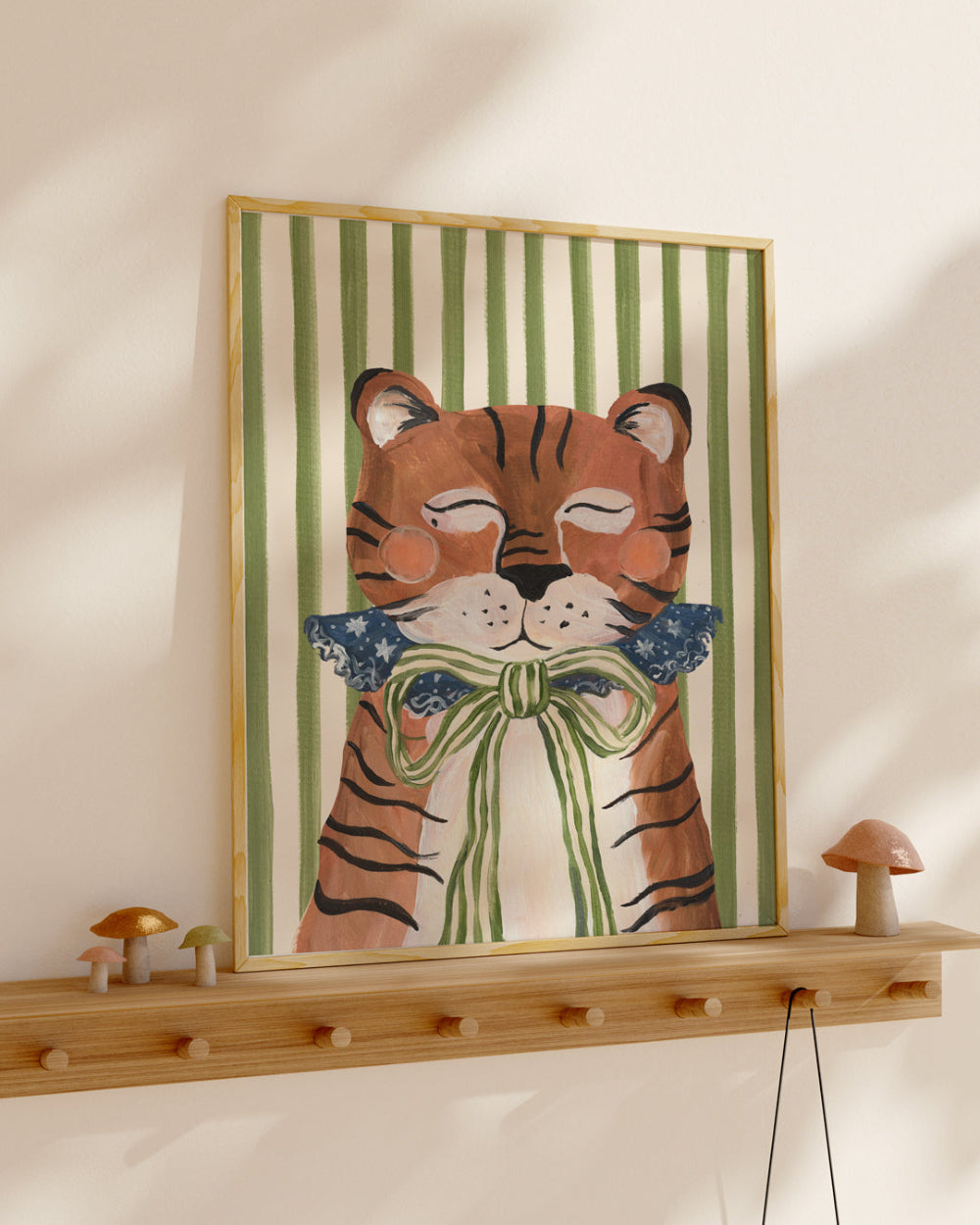 Framed artwork of a tiger with a bow tie on a wall above a wooden shelf.