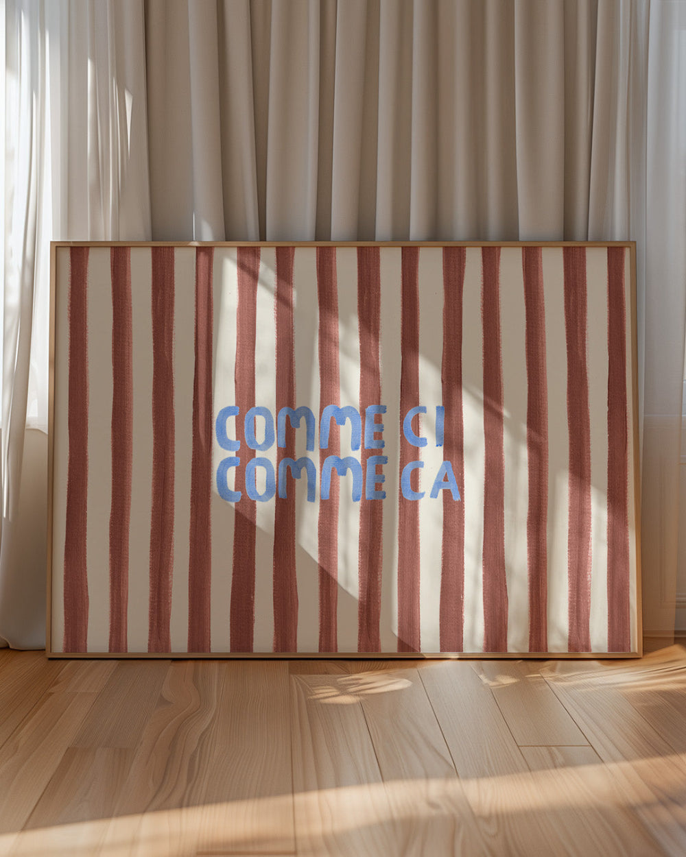 Striped artwork with 'COMME CI COMME CA' text in a wooden frame against a curtain backdrop.