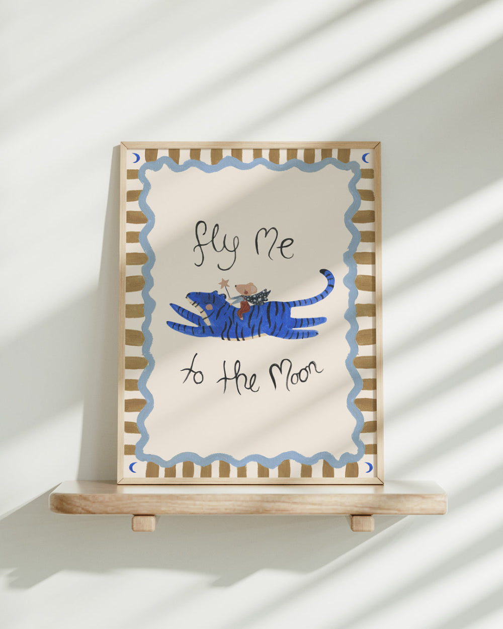 Framed artwork with a blue tiger and text 'fly me to the moon' on a white background
