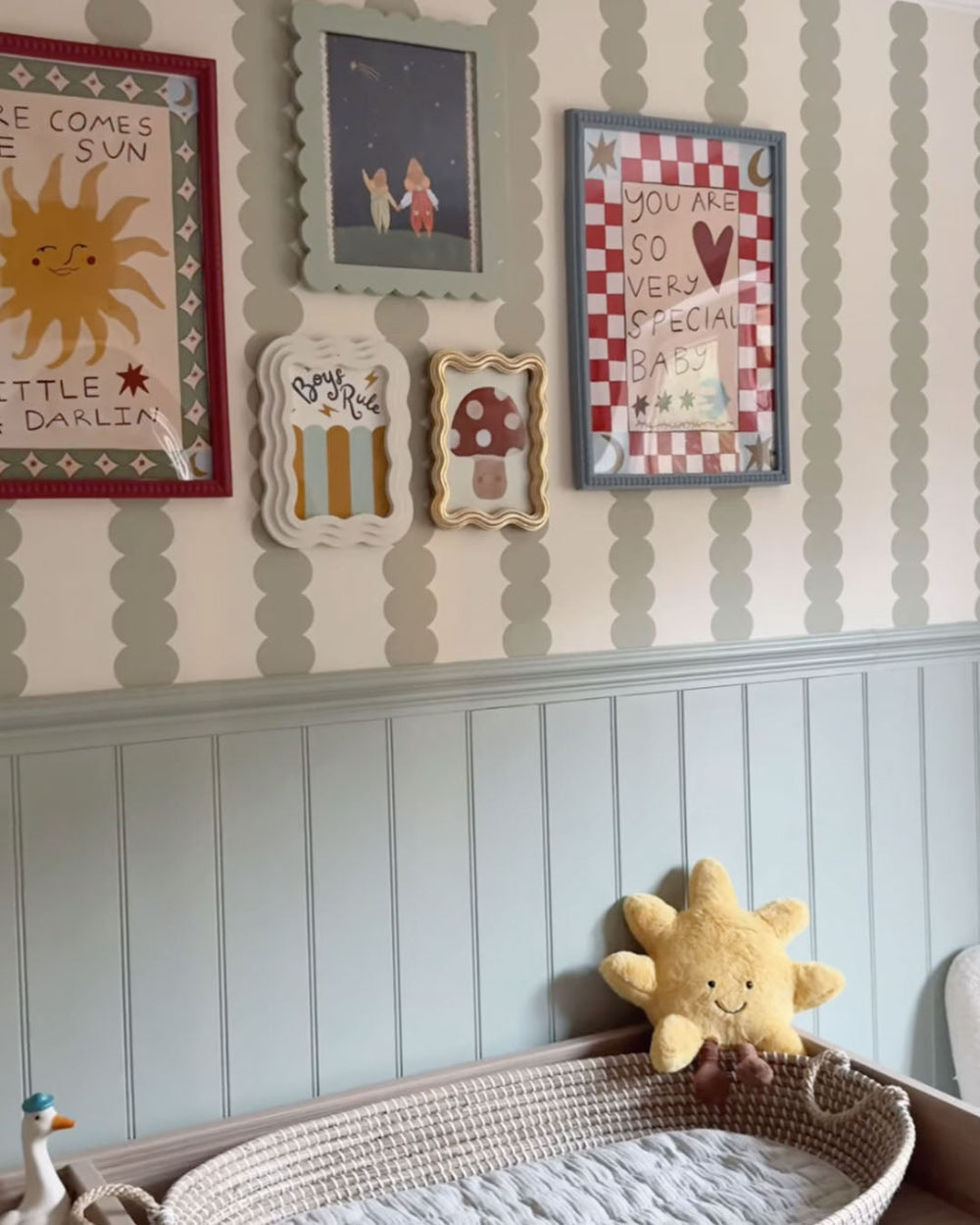 Nursery room with framed artwork and a sun-shaped plush toy.