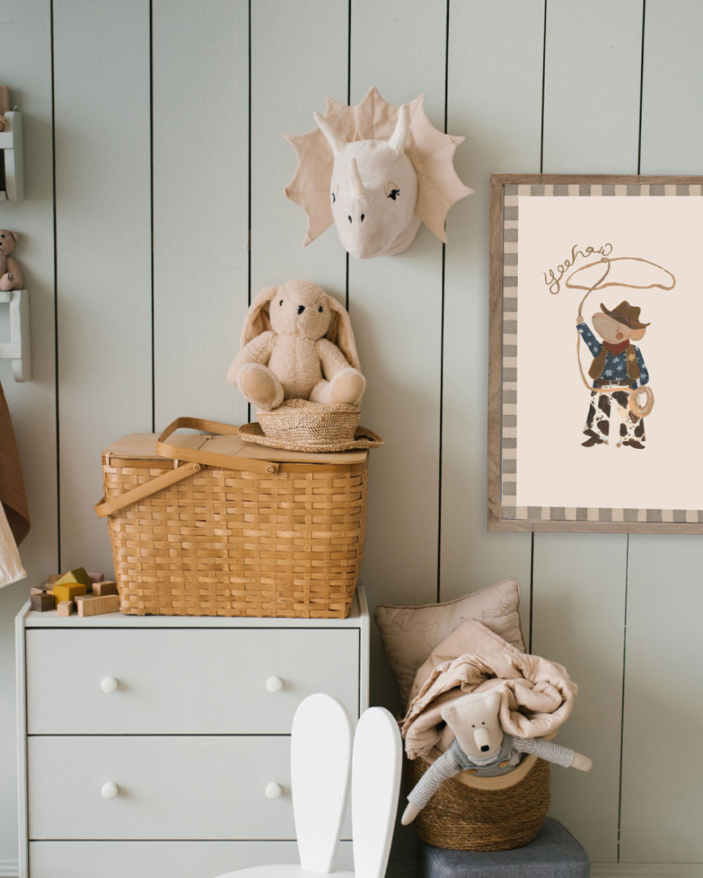 Children's room with toys, a basket, and a framed picture on a wooden wall.