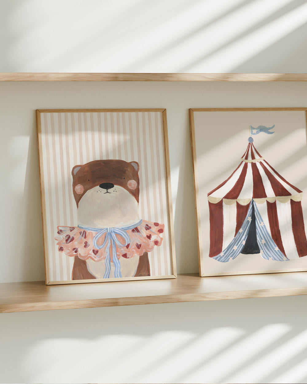 Two framed artworks Otter and Circus Tent on a shelf with a bear and circus tent design.