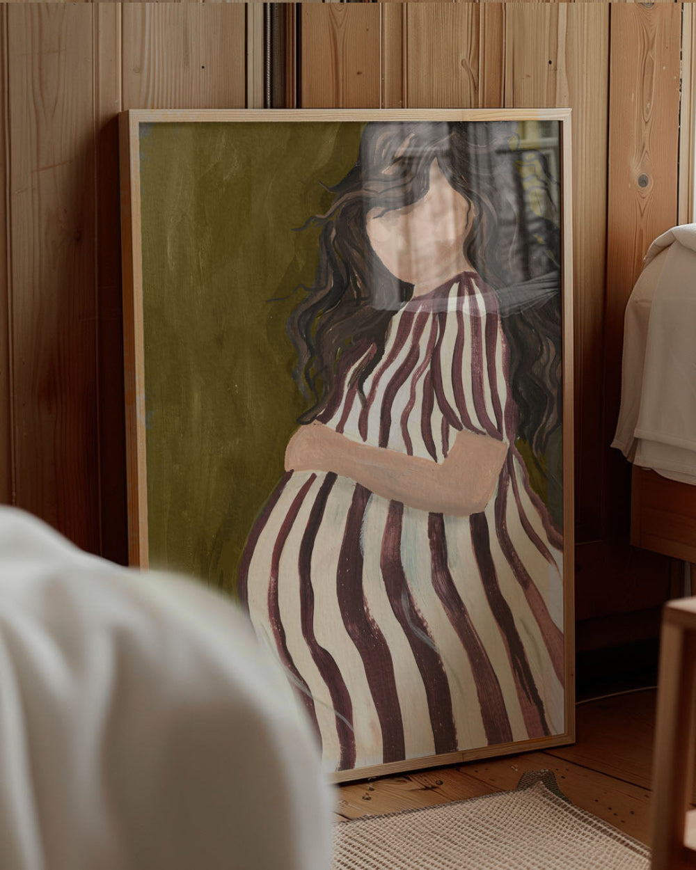 Framed artwork of a woman in a striped dress against a wooden wall.
