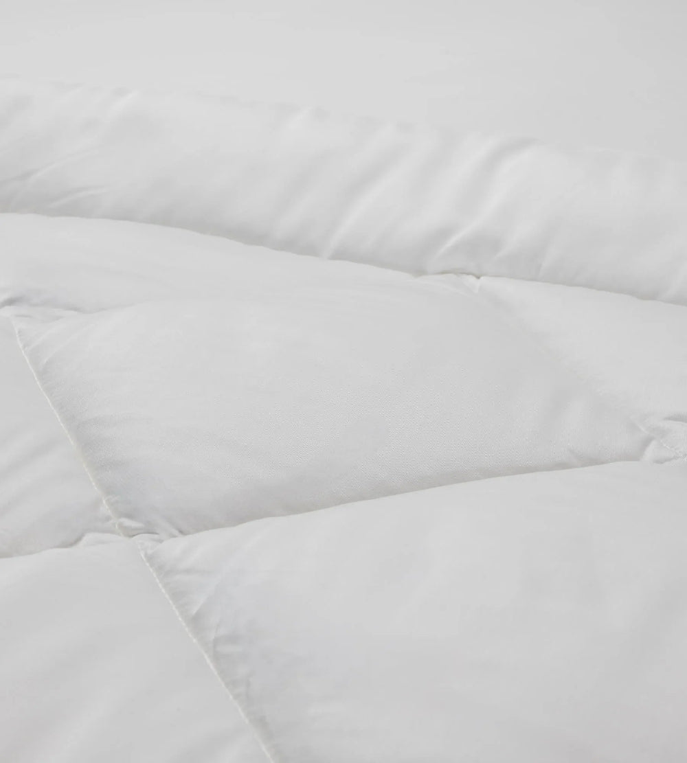 Close-up of a white quilted comforter with soft texture