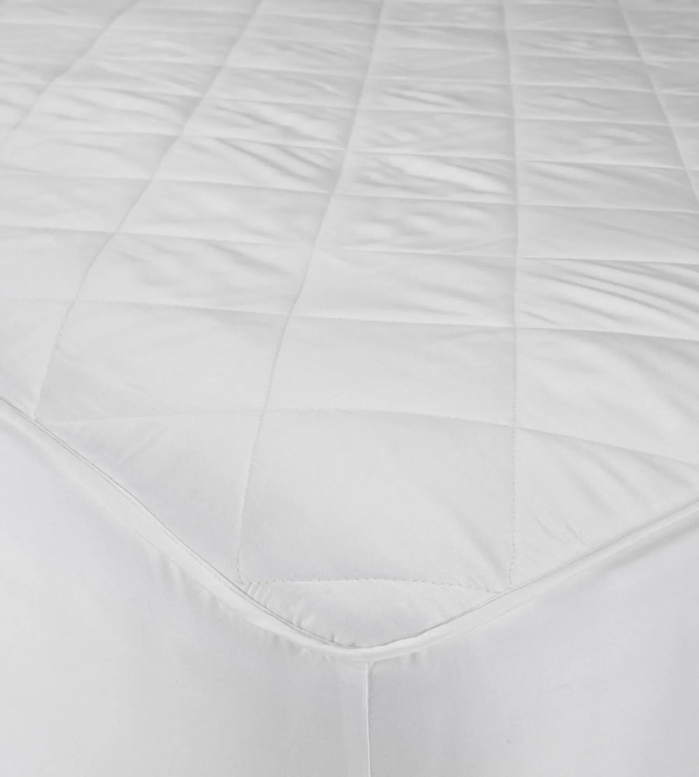 Close-up of a white quilted bamboo mattress protector with a textured surface.