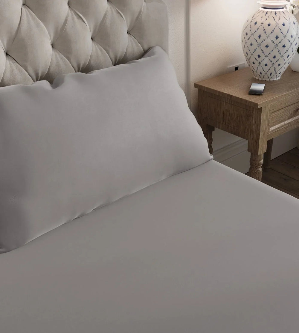 Grey bamboo bedding on a bed with a wooden nightstand and lamp in the background