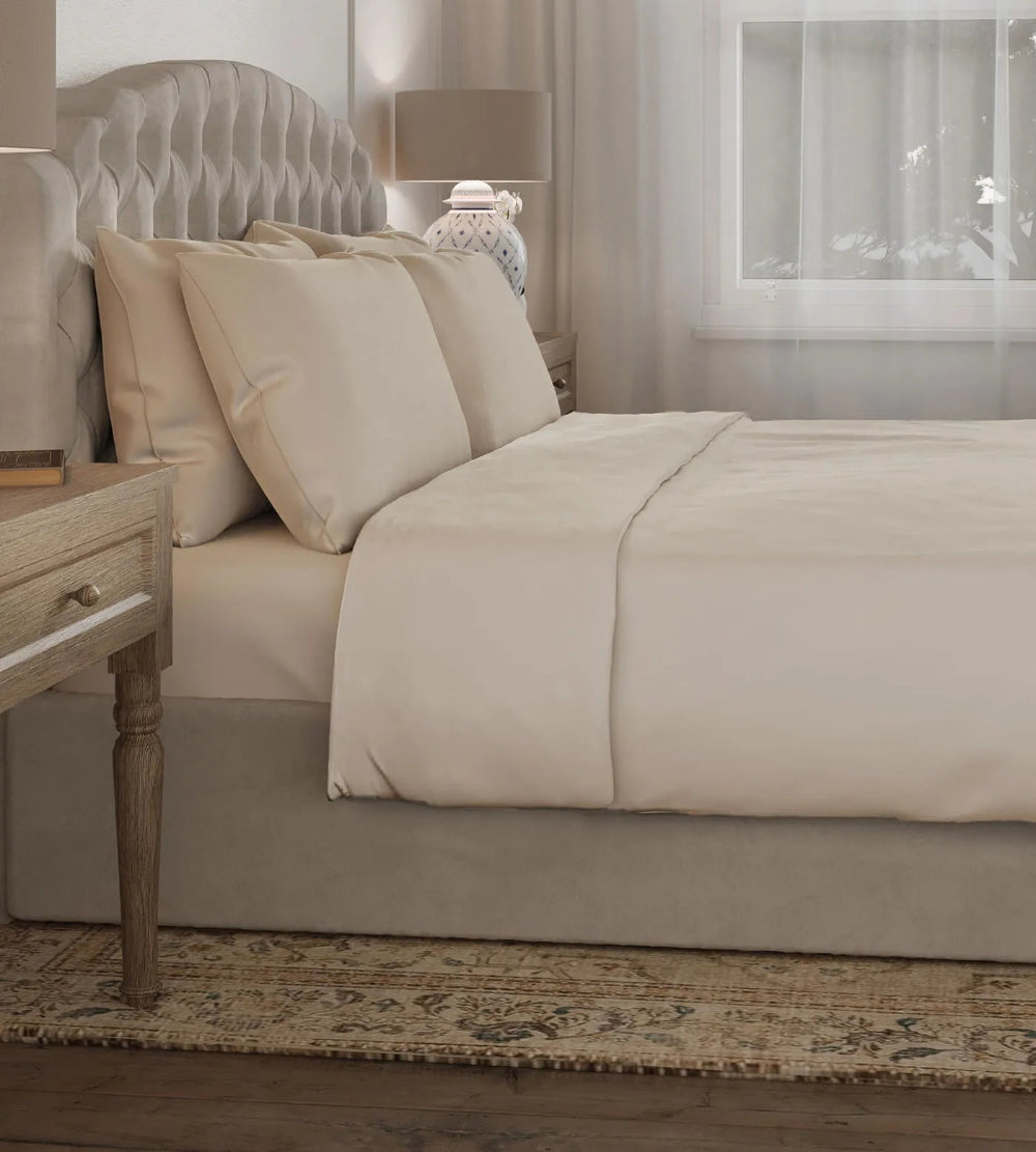 Neatly made Oatmeal covered duvet set bed in a bedroom setting.