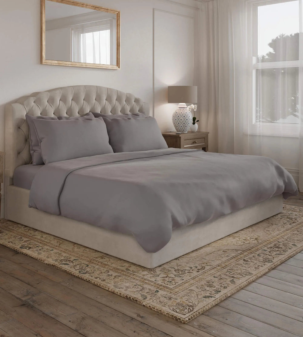 Neatly made bed with gray bedding in a bedroom setting.