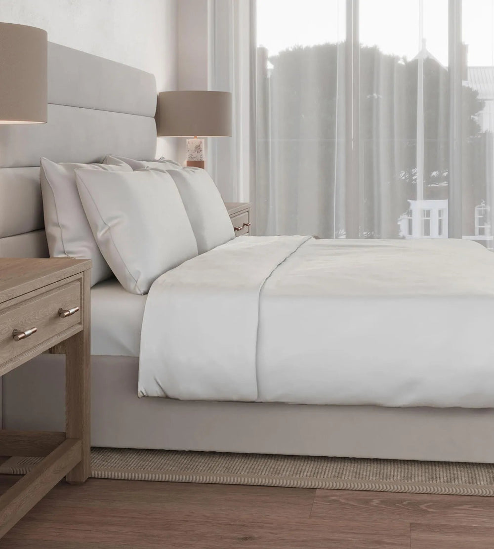 Neatly made bed with grey bedding in a modern bedroom setting.
