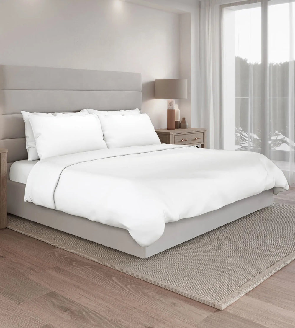 Neatly made bed with white bedding in a modern bedroom setting.