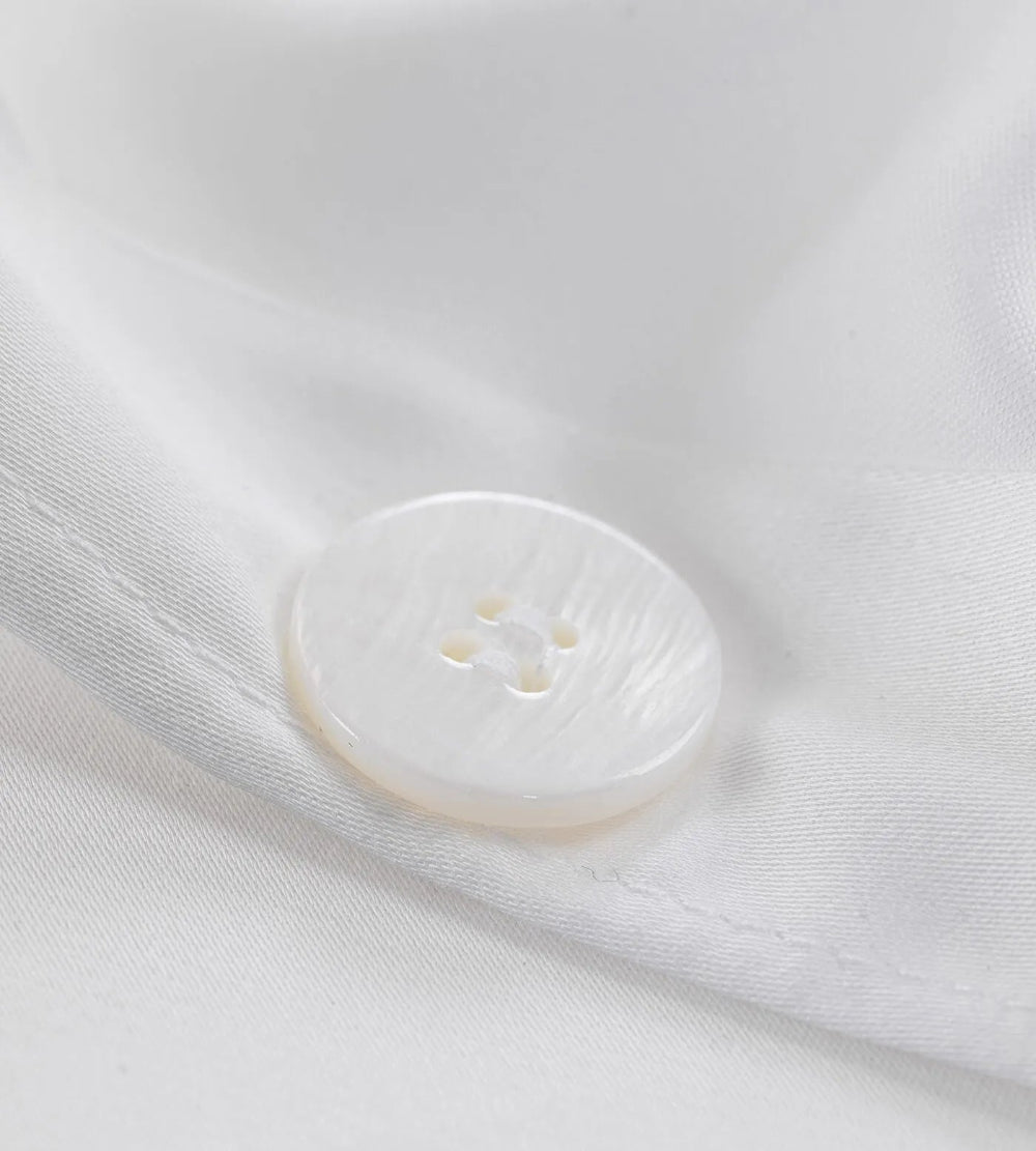 Close-up of a white button on a white fabric background