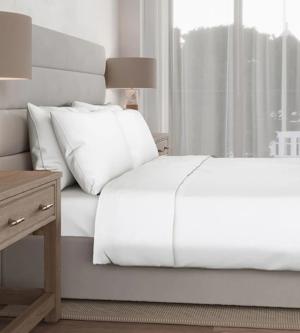 Neatly made bed with white bedding in a bedroom setting.