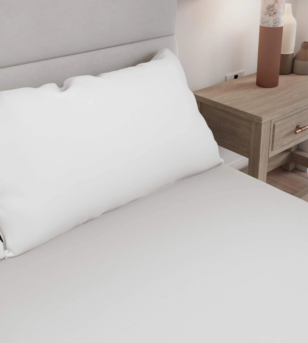 White pillow on a bed with a wooden nightstand in the background