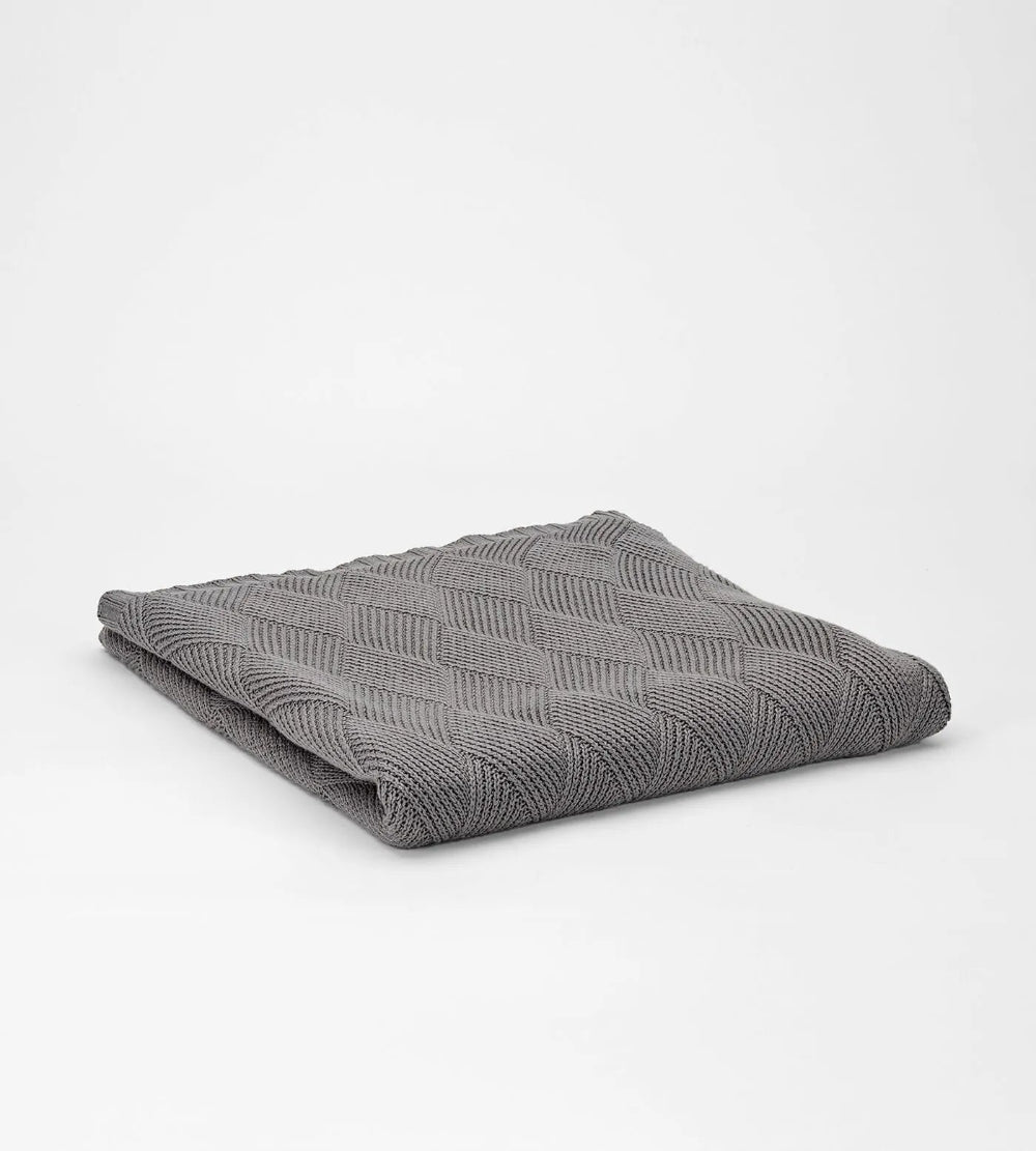 Folded grey textured blanket on a white background