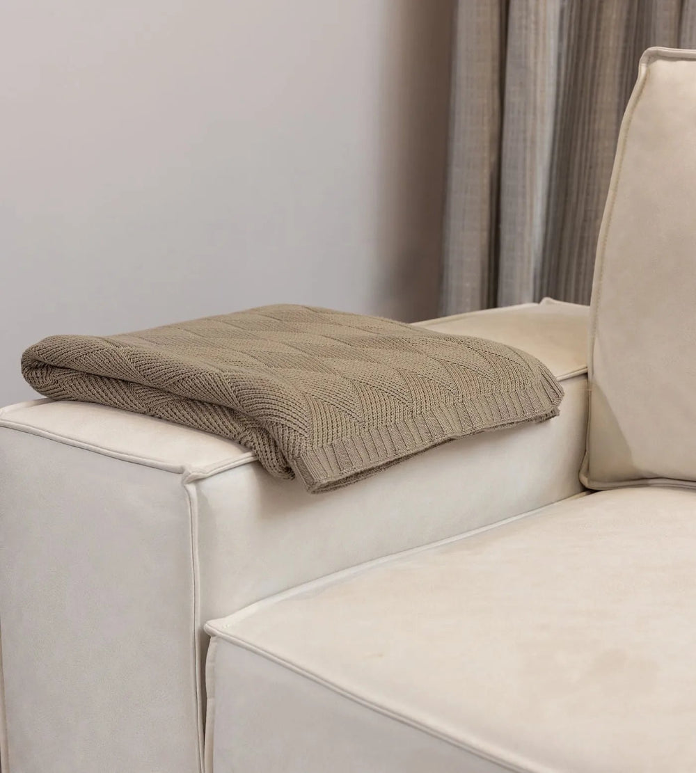 Beige blanket on a beige sofa with a neutral background