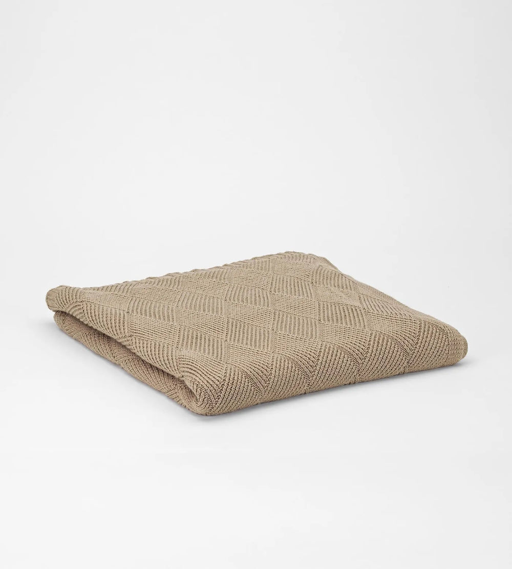 Folded beige blanket on a light grey background