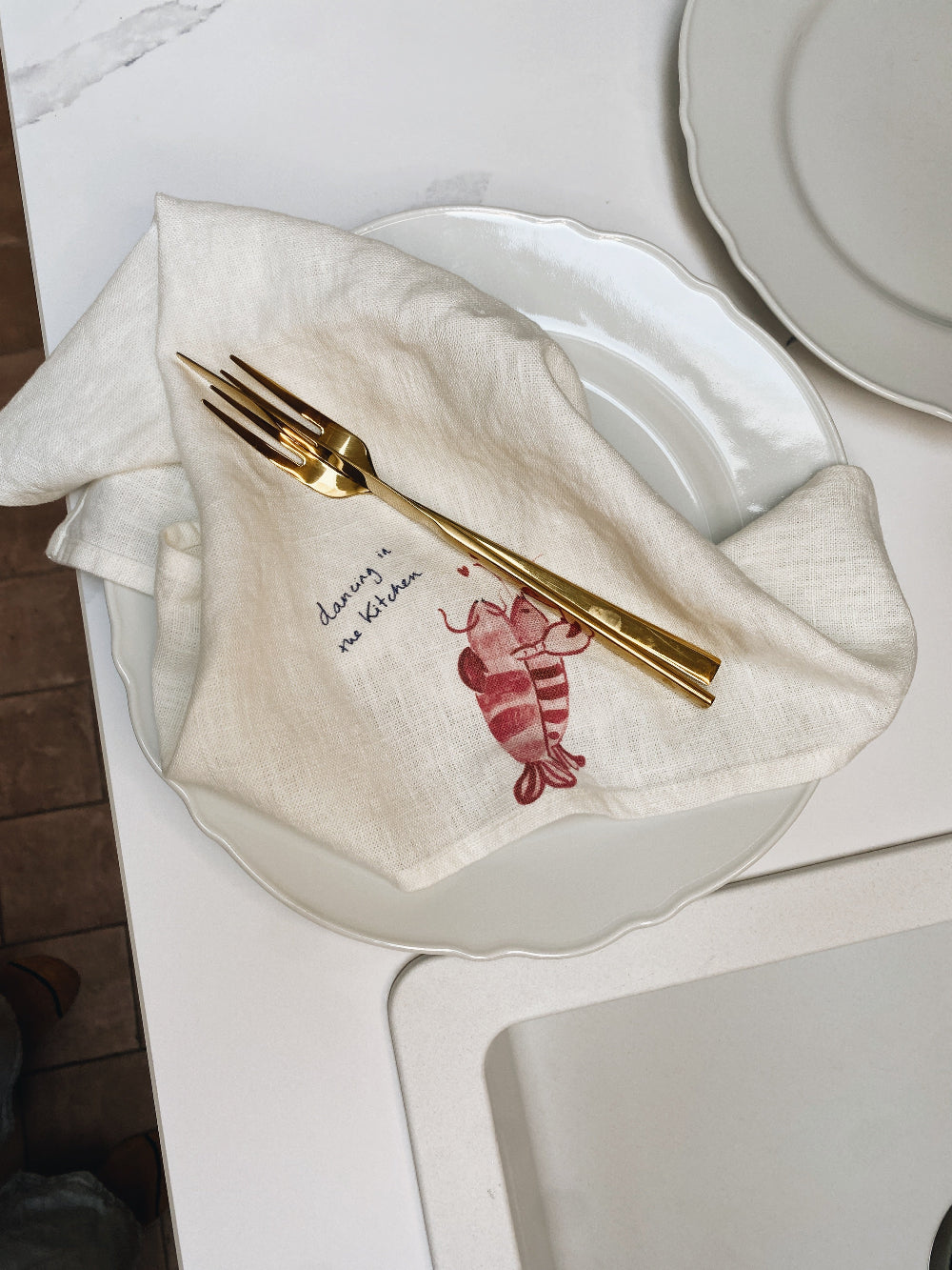 Napkin with lobster design and gold fork on a white plate