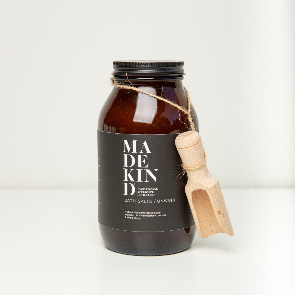 Bottle of Madekind bath salts with a wooden scoop on a white background