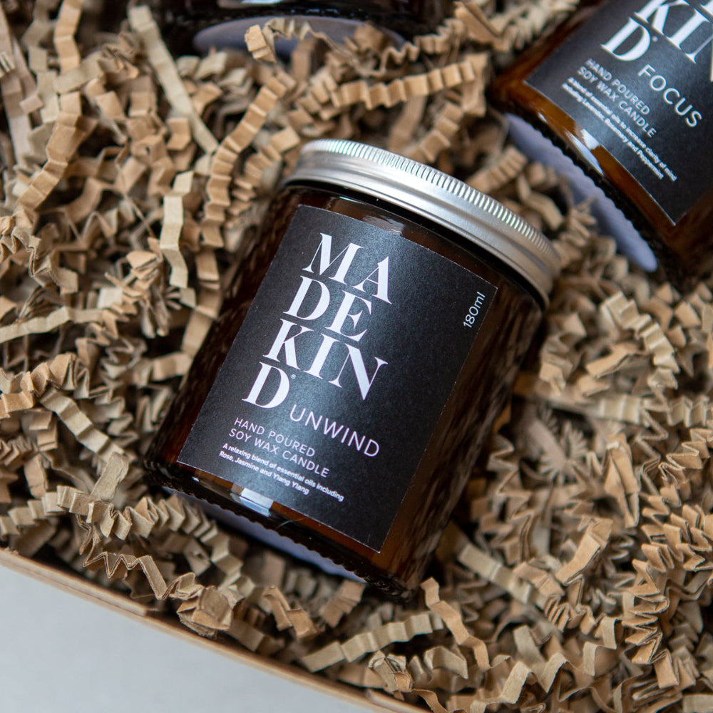 Candle jar labelled 'MADE KIND Unwind' on crinkled brown paper
