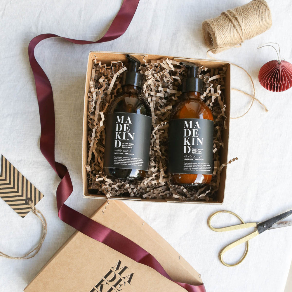 Two bottles of Madekind hand lotion in a gift box with ribbons and scissors on a white background