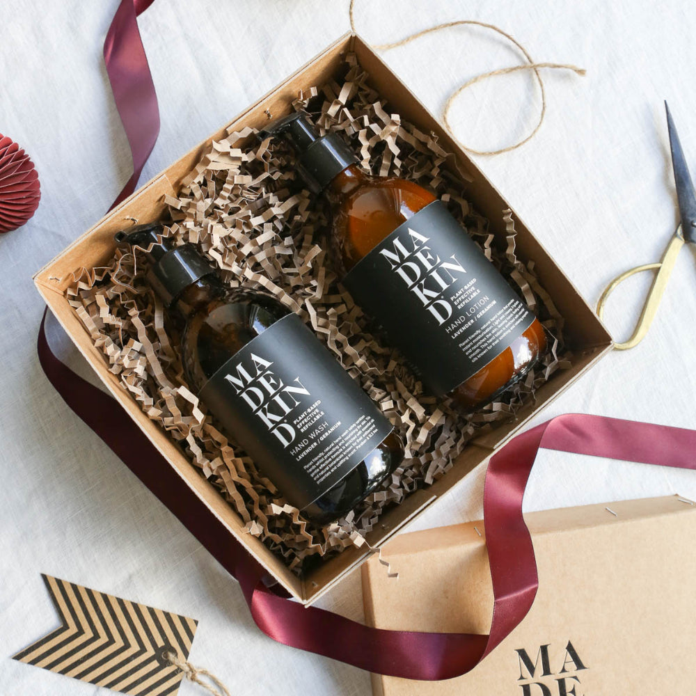 Two bottles of 'MADEKIND' in a gift box with ribbons and scissors on a light background