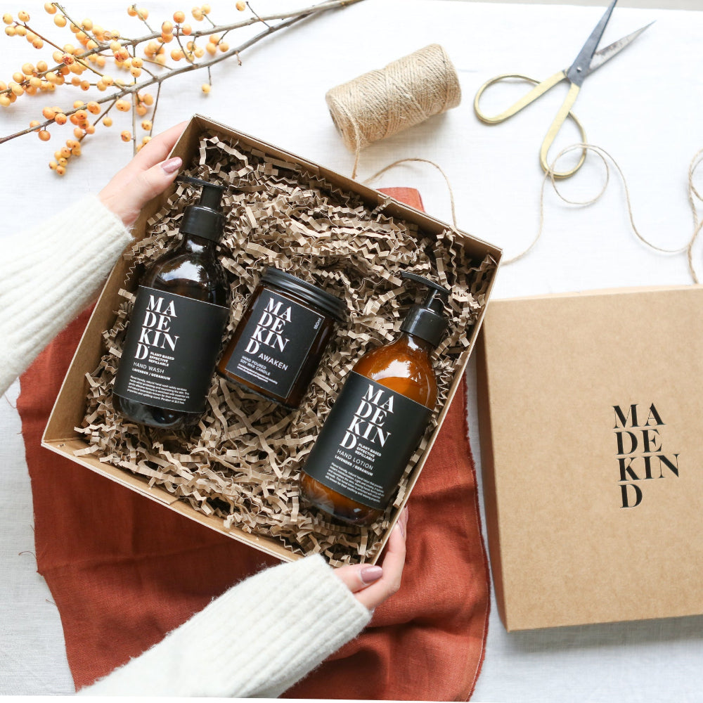 Three bottles of Madekind skincare products in a box on a white surface with decorative elements.