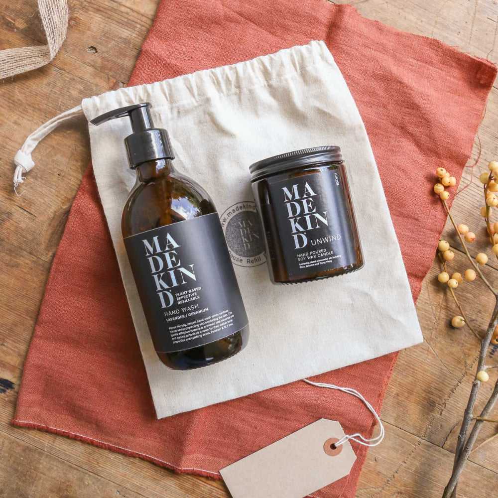Madekind hand wash bottle and candle jar on a drawstring bag with a tag on a wooden surface.